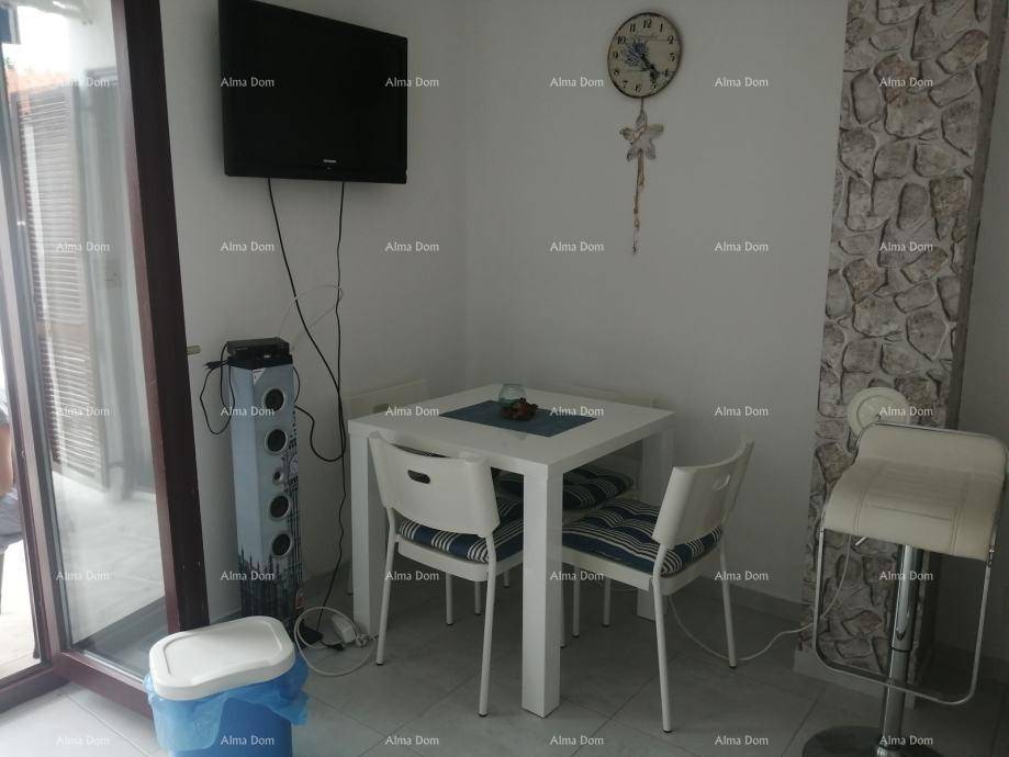 Kleiner Essbereich mit modernem Tisch, Stühlen und einem Fernseher an der Wand.