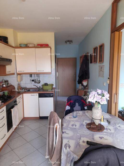 Funktionale Küche mit weißen Schränken, Fliesenboden und integriertem Essbereich.
