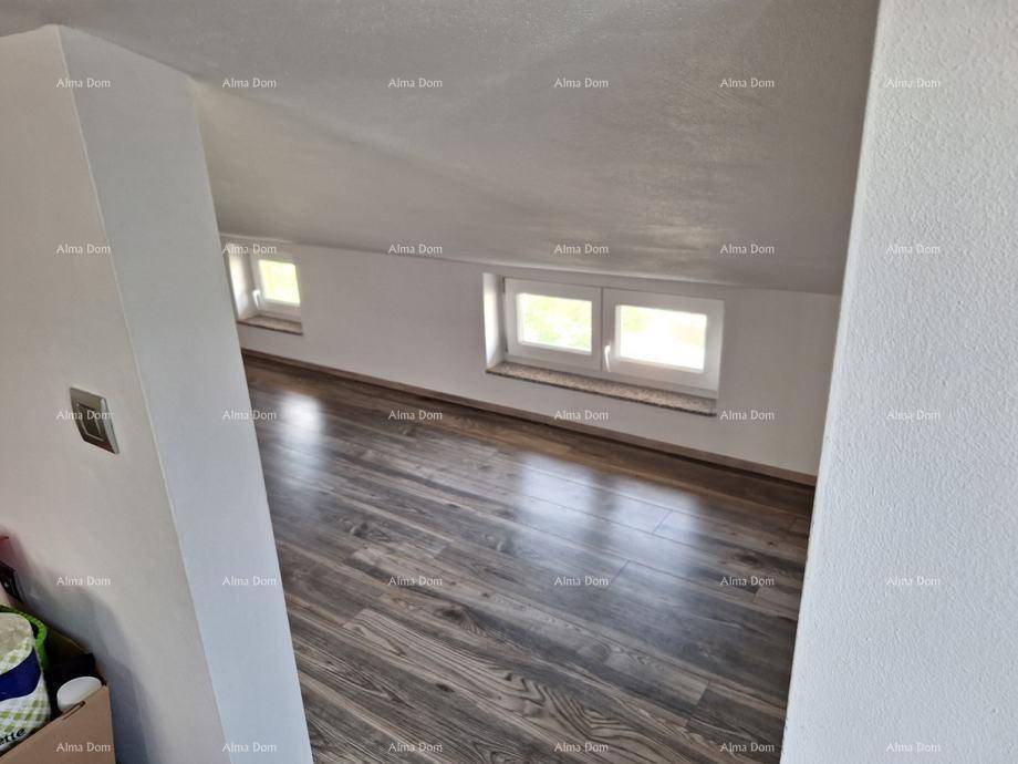 Heller Raum mit Laminatboden und mehreren Fenstern unter einer Dachschräge.
