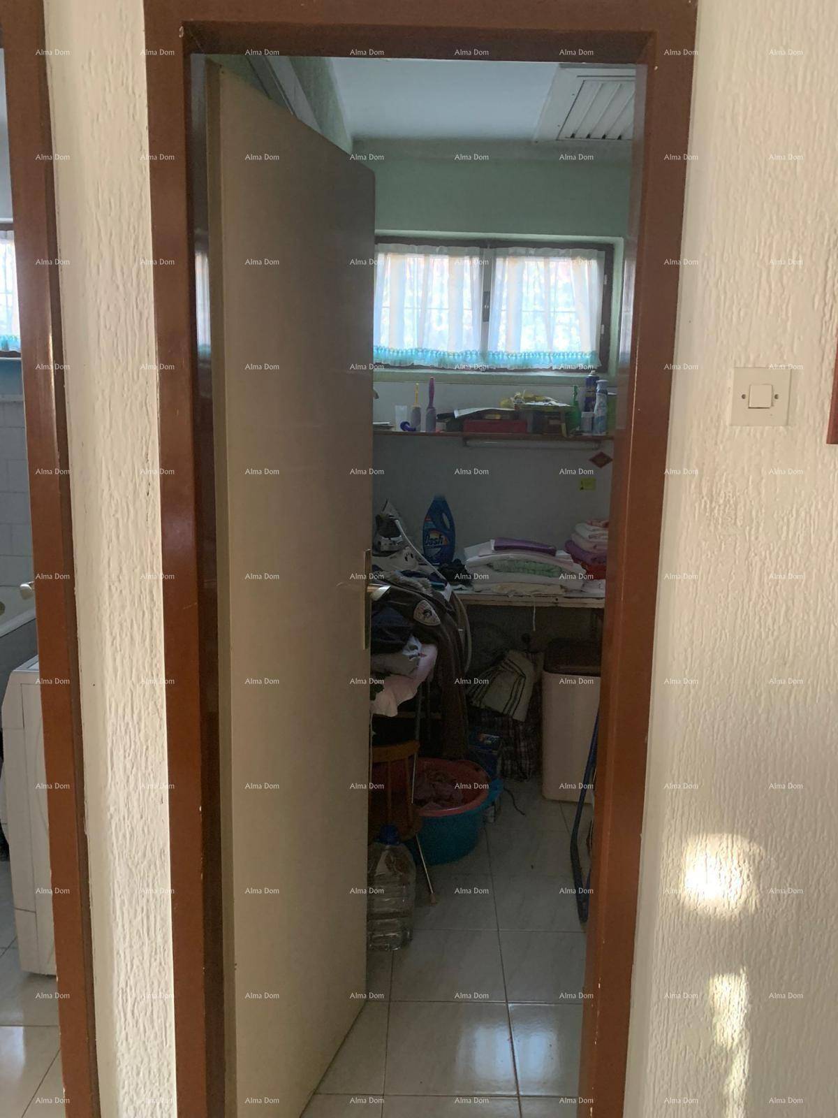 Blick durch eine Tür in einen Hauswirtschaftsraum mit Fliesenboden und einem Fenster.