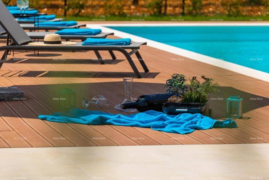 Detailaufnahme des Poolbereichs mit Holzdeck, Liegestühlen und blauen Handtüchern in der Sonne.