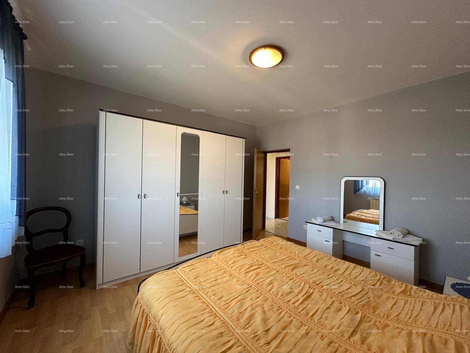 Schlafzimmer mit großem Kleiderschrank, Schminktisch und Holzboden, funktional eingerichtet.