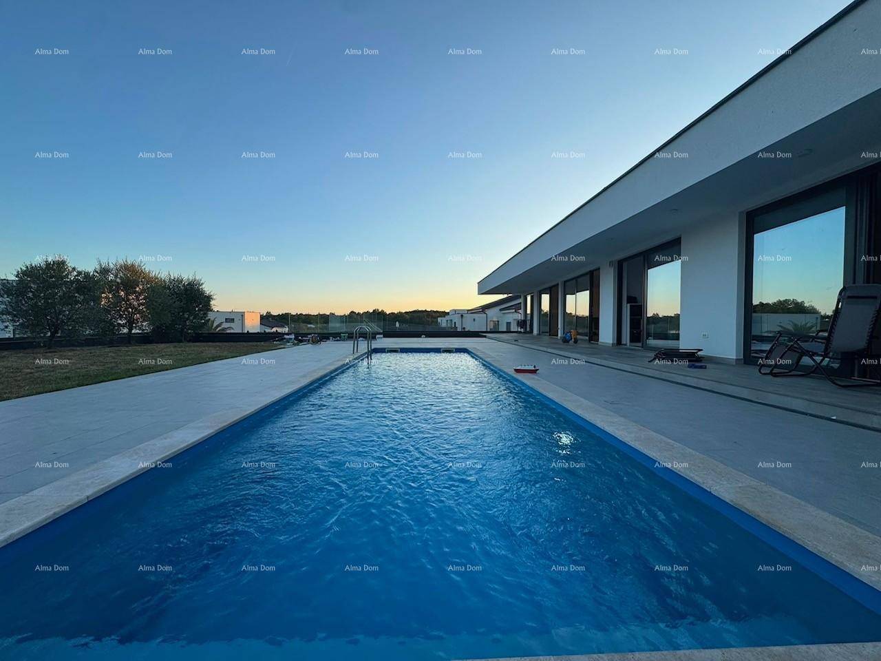 Langer Swimmingpool neben der modernen Villa bei Sonnenuntergang mit weitem Blick in die Landschaft.