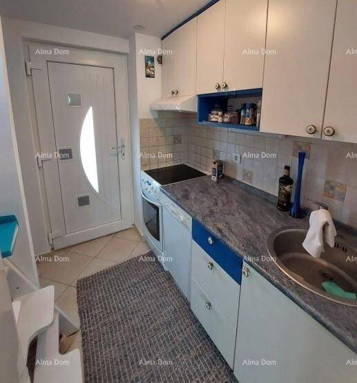 Funktionale Küchenzeile mit weißen Schränken, Spüle und Herd, direkt neben der Eingangstür.