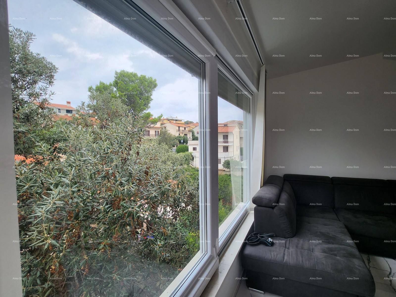 Gemütliches Wohnzimmer mit dunklem Ecksofa und weitem Blick auf grüne Bäume und Häuser.