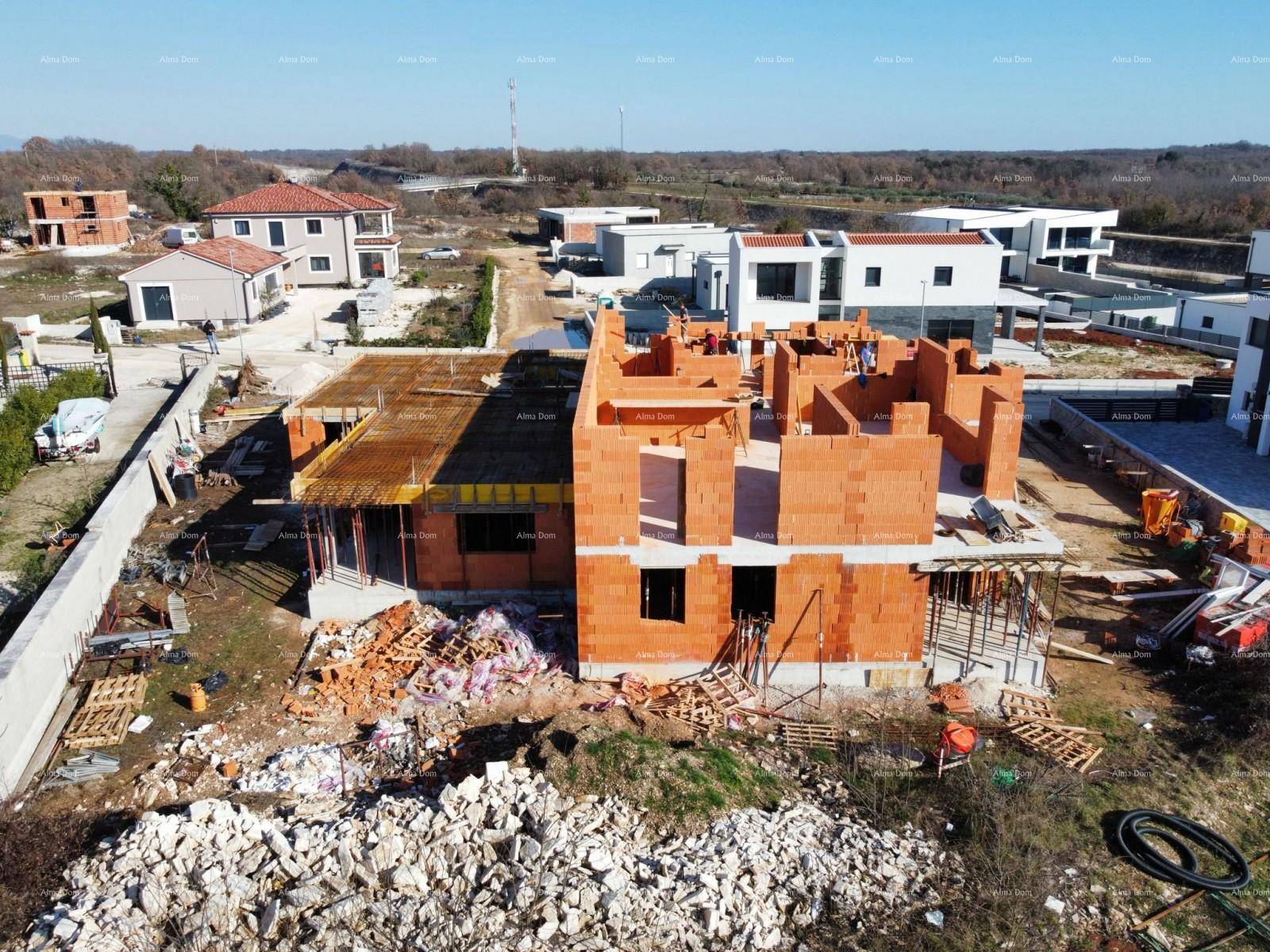 Überblick aus der Luft über eine Baustelle mit Rohbauten und der weiteren Umgebung unter blauem Himmel.