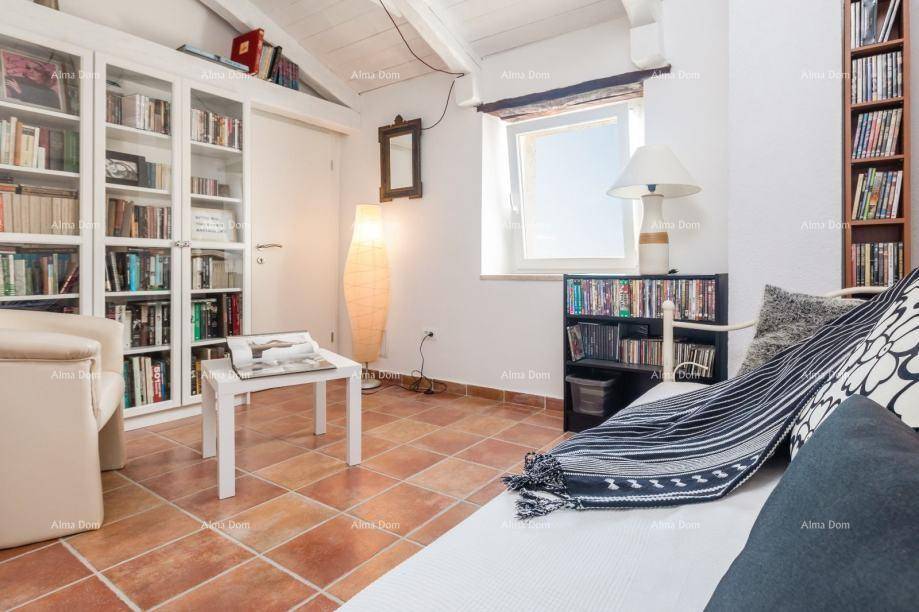 Helles Wohnzimmer mit Bücherregalen, Terrakottaboden und sichtbaren Holzbalken an der Decke.