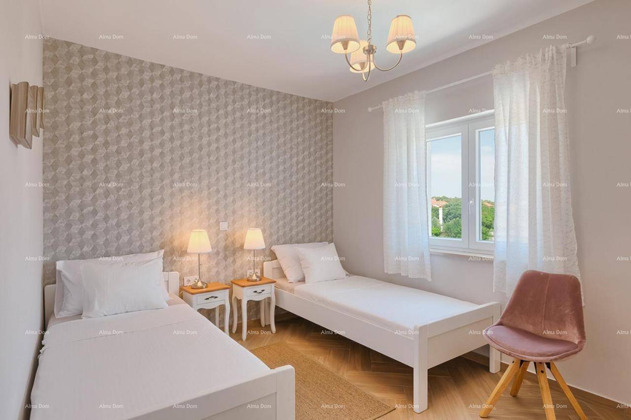 Helles Schlafzimmer mit zwei Einzelbetten, gemusterter Tapete und Fenster mit Vorhängen.