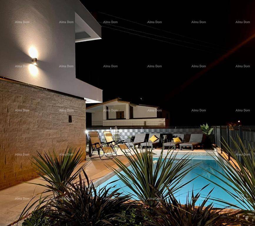 Beleuchteter Poolbereich bei Nacht mit Liegestühlen und Pflanzen.