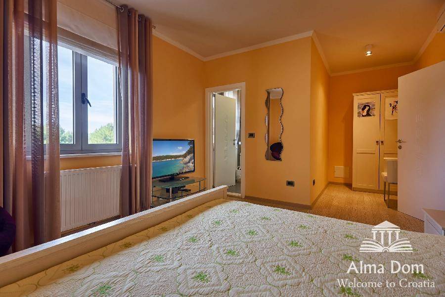 Schlafzimmer mit orangefarbenen Wänden, Fenster und Blick auf die grüne Umgebung.