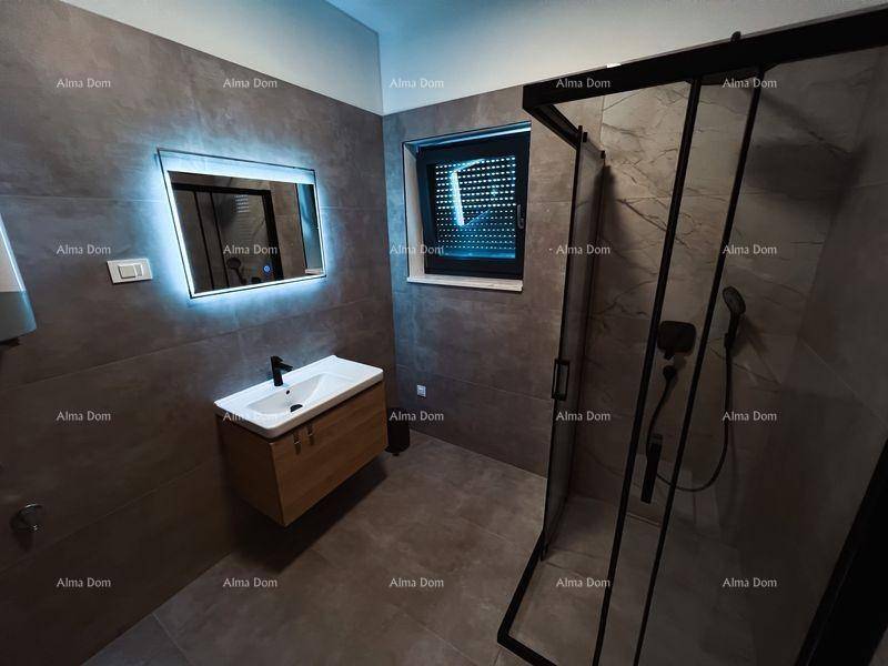 Modernes Badezimmer mit grauen Fliesen, schwebendem Waschtisch, beleuchtetem Spiegel und begehbarer Dusche.