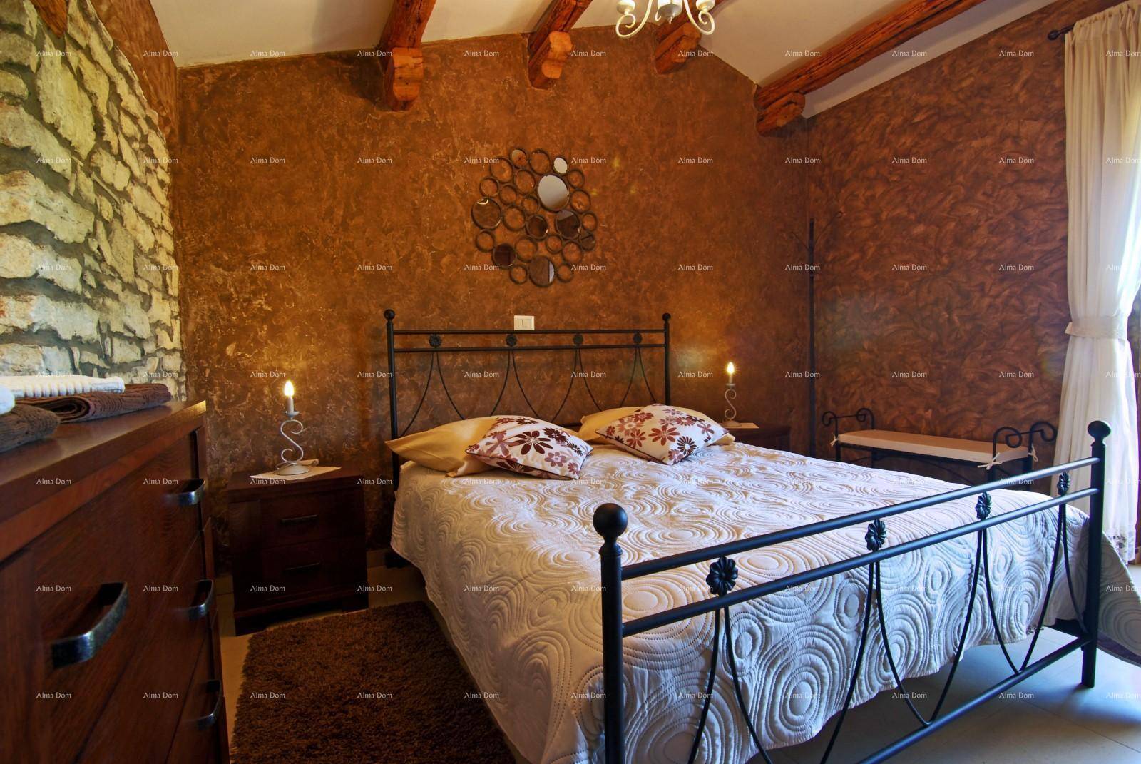 Schlafzimmer im Landhausstil mit schmiedeeisernem Bett, Holzbalken und einer Steinwand.