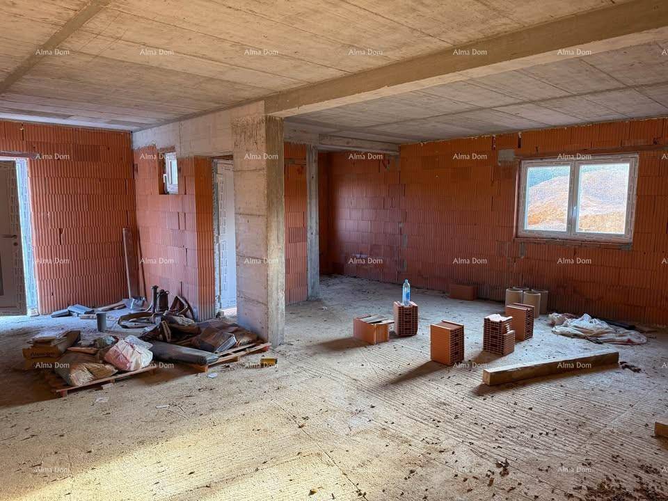 Großer, unfertiger Innenraum mit Ziegelwänden, Betonboden und Fenstern, die den Blick nach draußen freigeben.