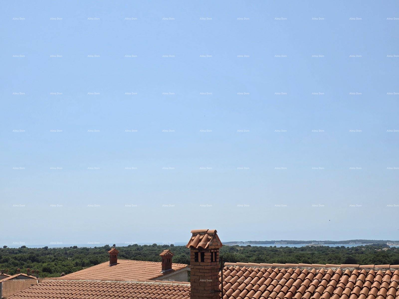 Weiter Ausblick über Ziegeldächer, üppiges Grün und das glitzernde Meer in der Ferne an einem sonnigen Tag.