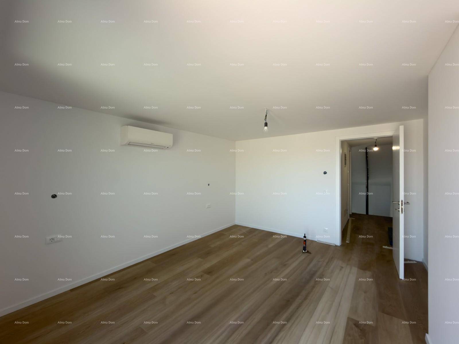 Leeres Zimmer mit Holzboden, Klimaanlage und weißen Wänden, bereit für die Einrichtung.