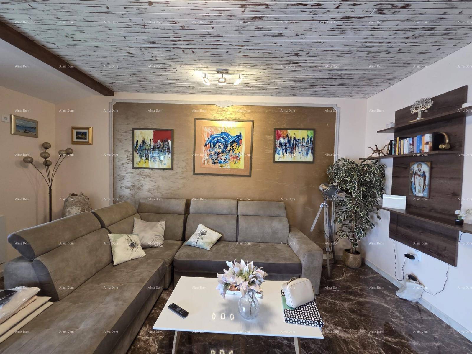 Gemütliches Wohnzimmer mit Ecksofa, Kunstwerken und Holzbalkendecke.