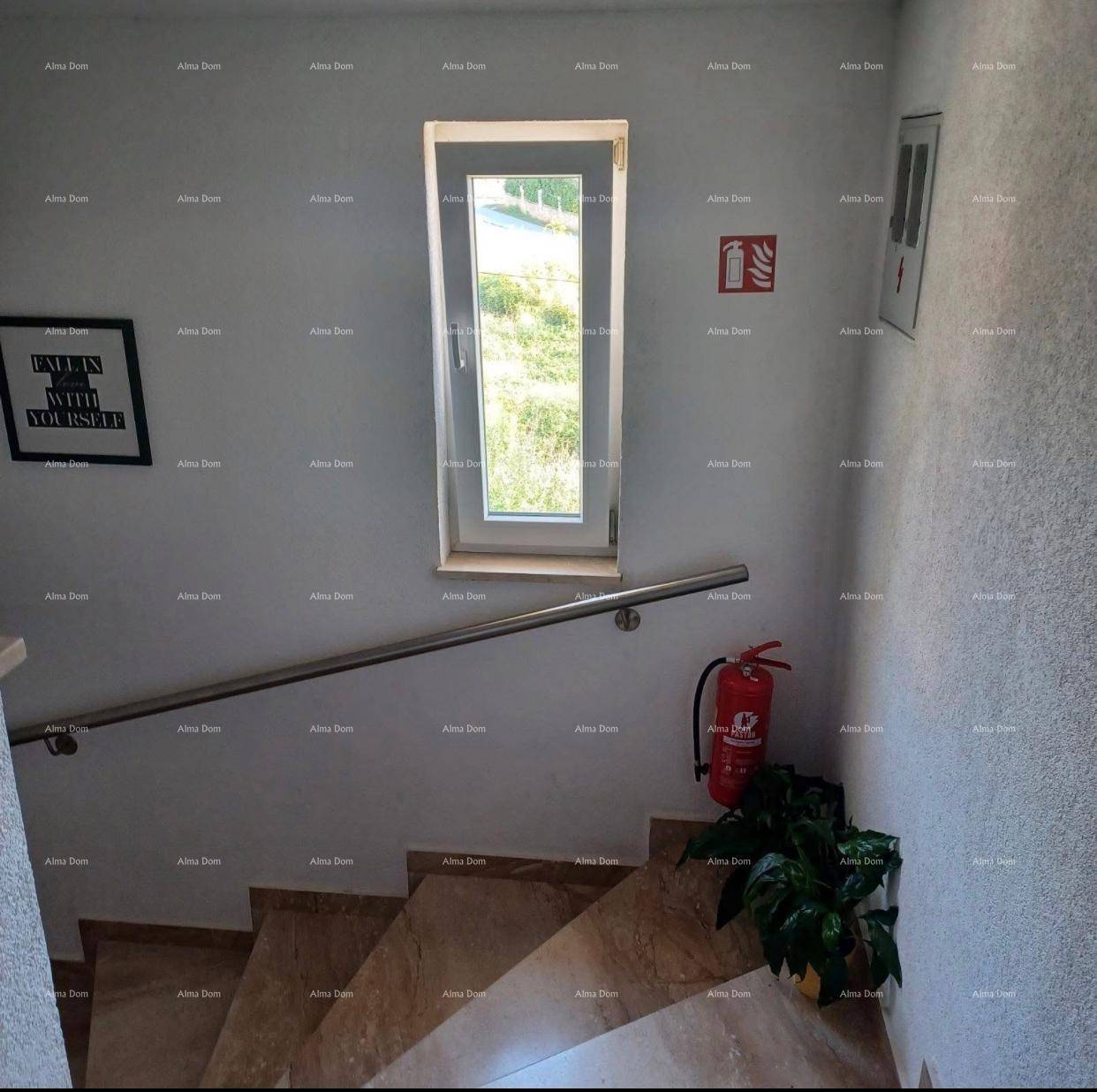Treppenhaus mit Marmorstufen, einem stabilen Handlauf und einem hohen Fenster für Tageslicht.