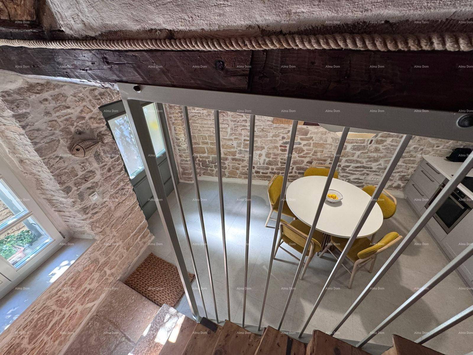 Blick von der Treppe auf den Essbereich und die Küche mit Steinwänden und Holzbalken.
