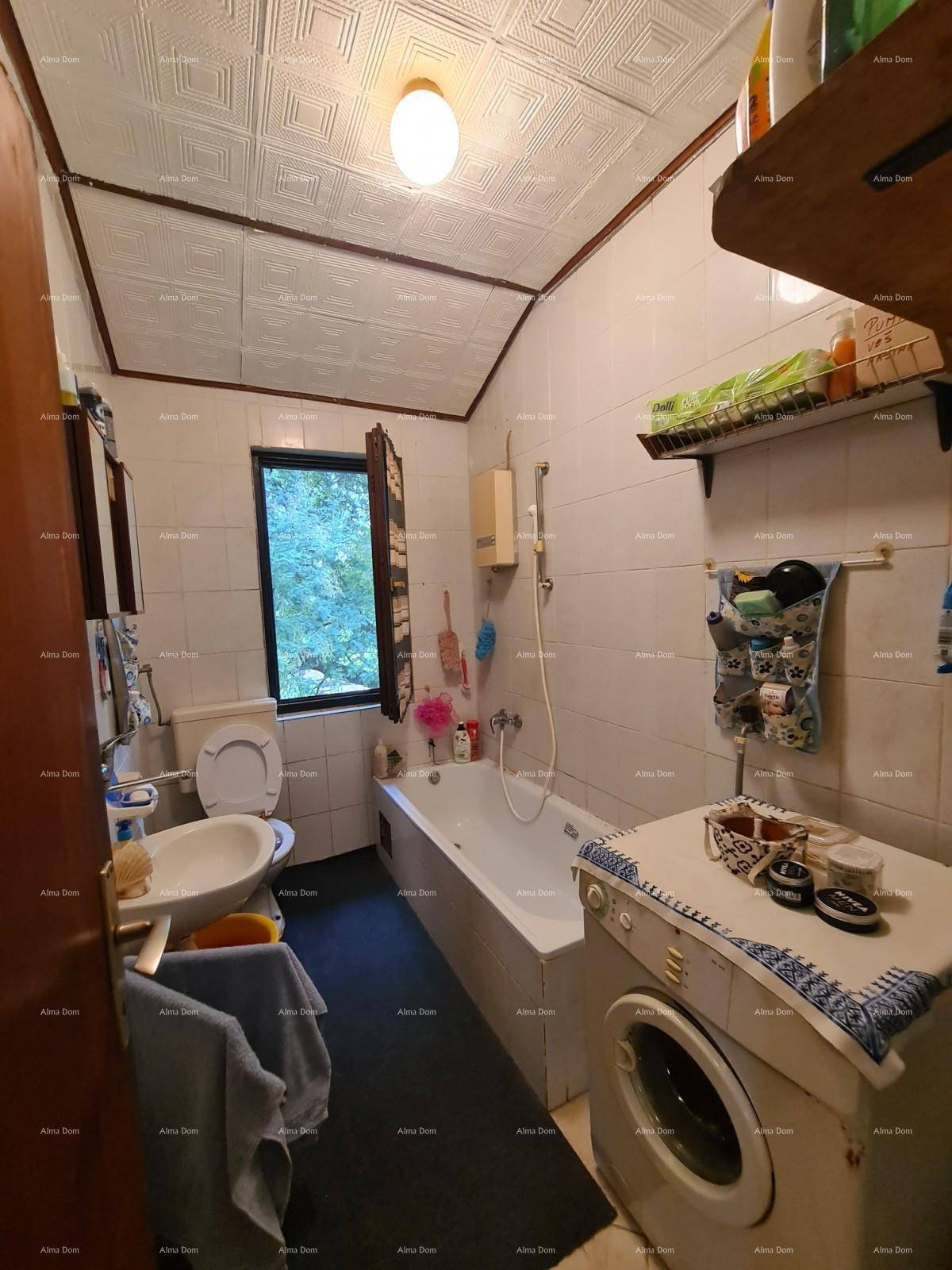 Einfaches Badezimmer mit Badewanne, Waschbecken, Toilette und einem Fenster für Tageslicht.