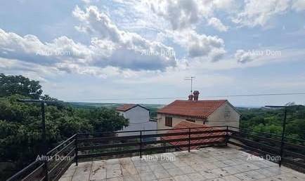 Große Dachterrasse mit weitem Blick über die grüne Landschaft und andere Dächer unter bewölktem Himmel.