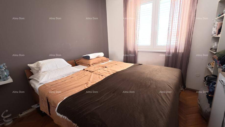 Schlafzimmer mit Doppelbett, Parkettboden und Fenster mit Vorhängen für Privatsphäre.