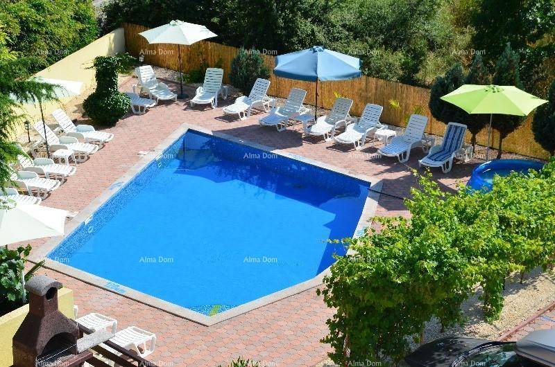 Großer Außenpool mit Liegestühlen, Sonnenschirmen und gepflasterter Fläche.