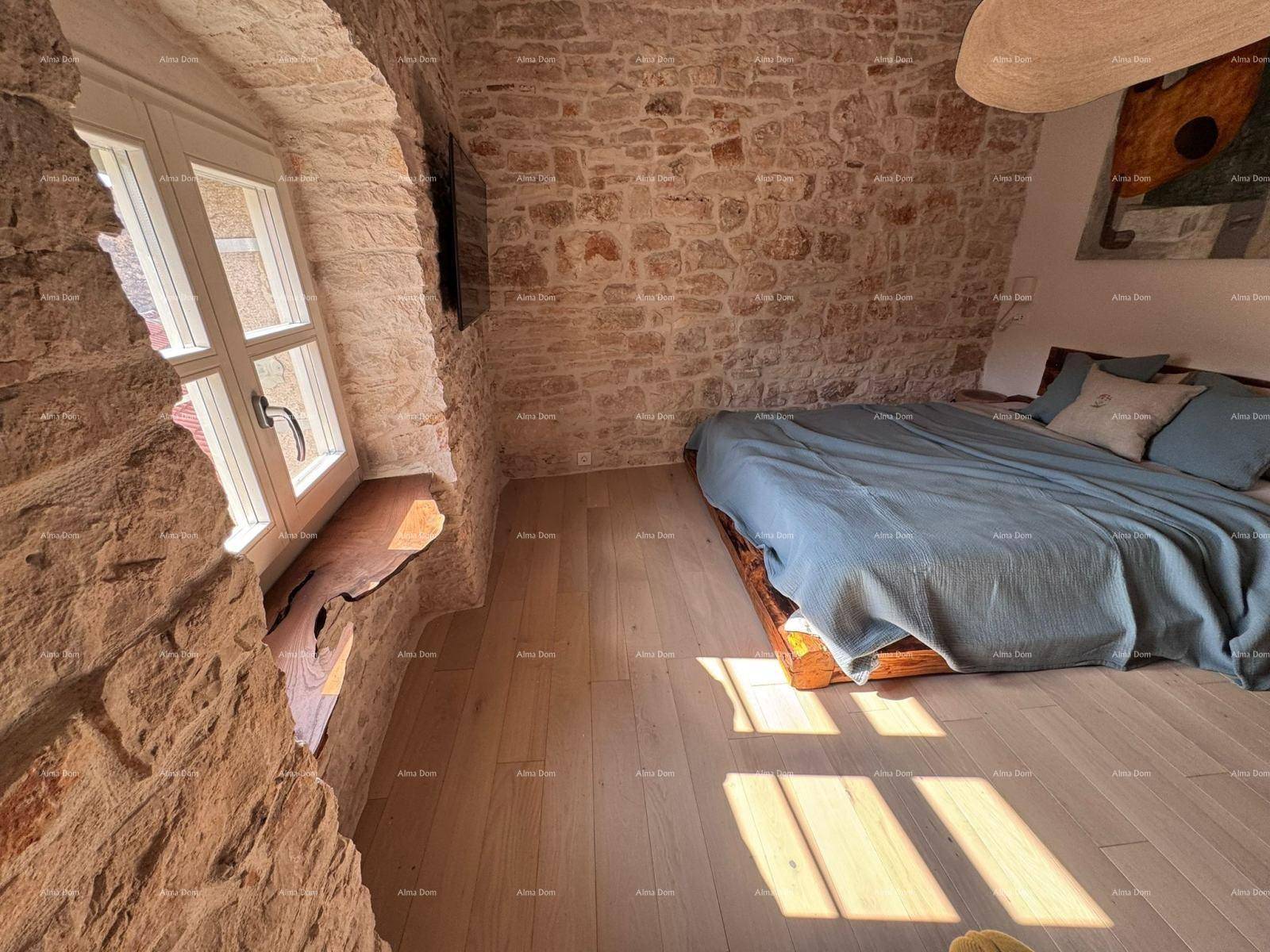 Schlafzimmer mit Holzboden, Steinwänden und einem Fenster mit viel Tageslicht.