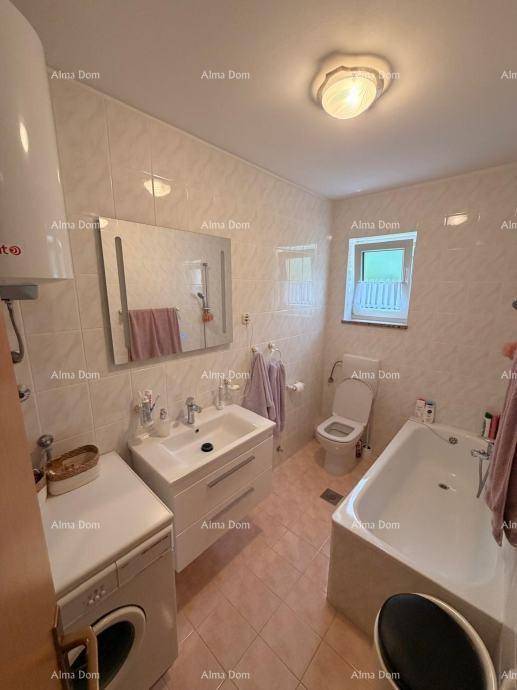 Badezimmer mit Badewanne, Waschbecken, Toilette, Fenster und Waschmaschine.