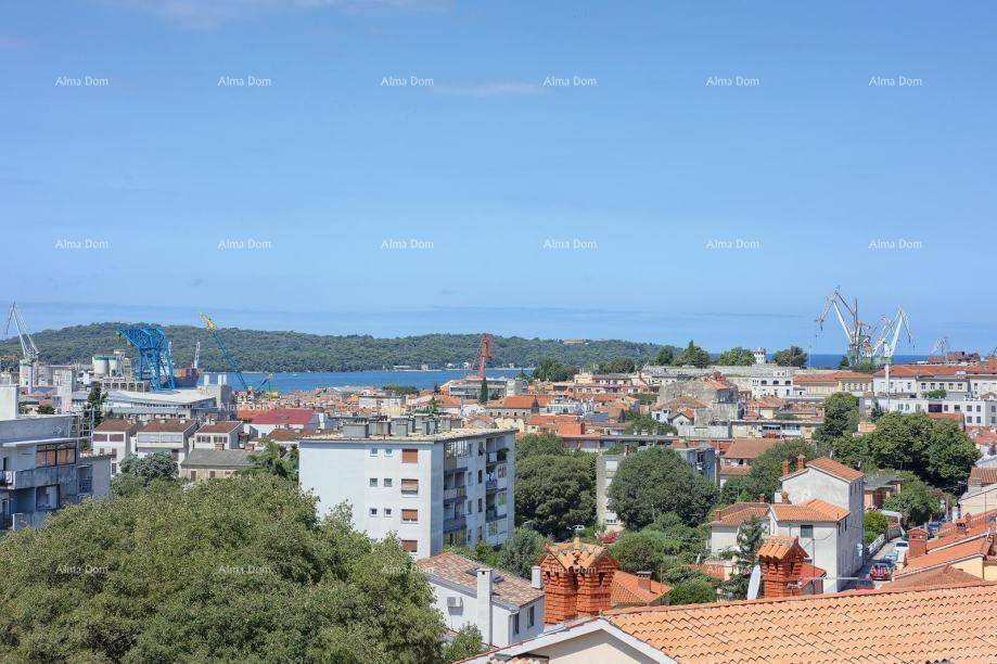 Panoramablick über die Stadt, das Meer und den Hafen mit Kränen unter blauem Himmel.
