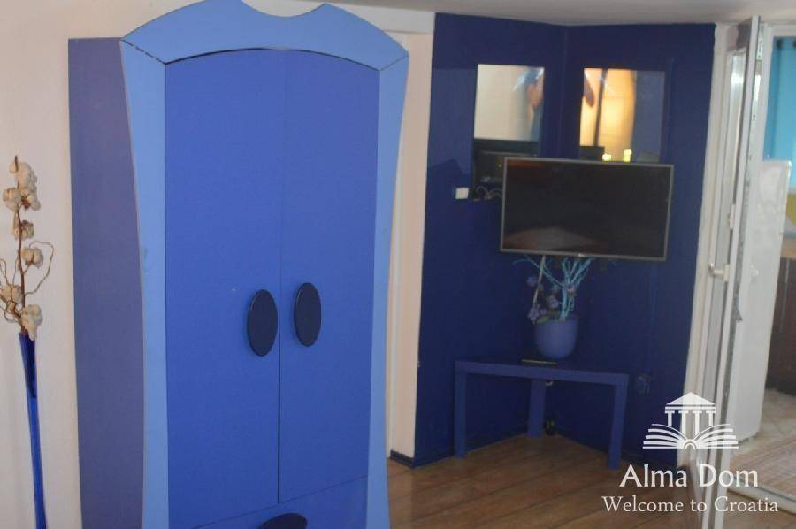 Flur mit auffälligem blauen Kleiderschrank und wandmontiertem Fernseher.