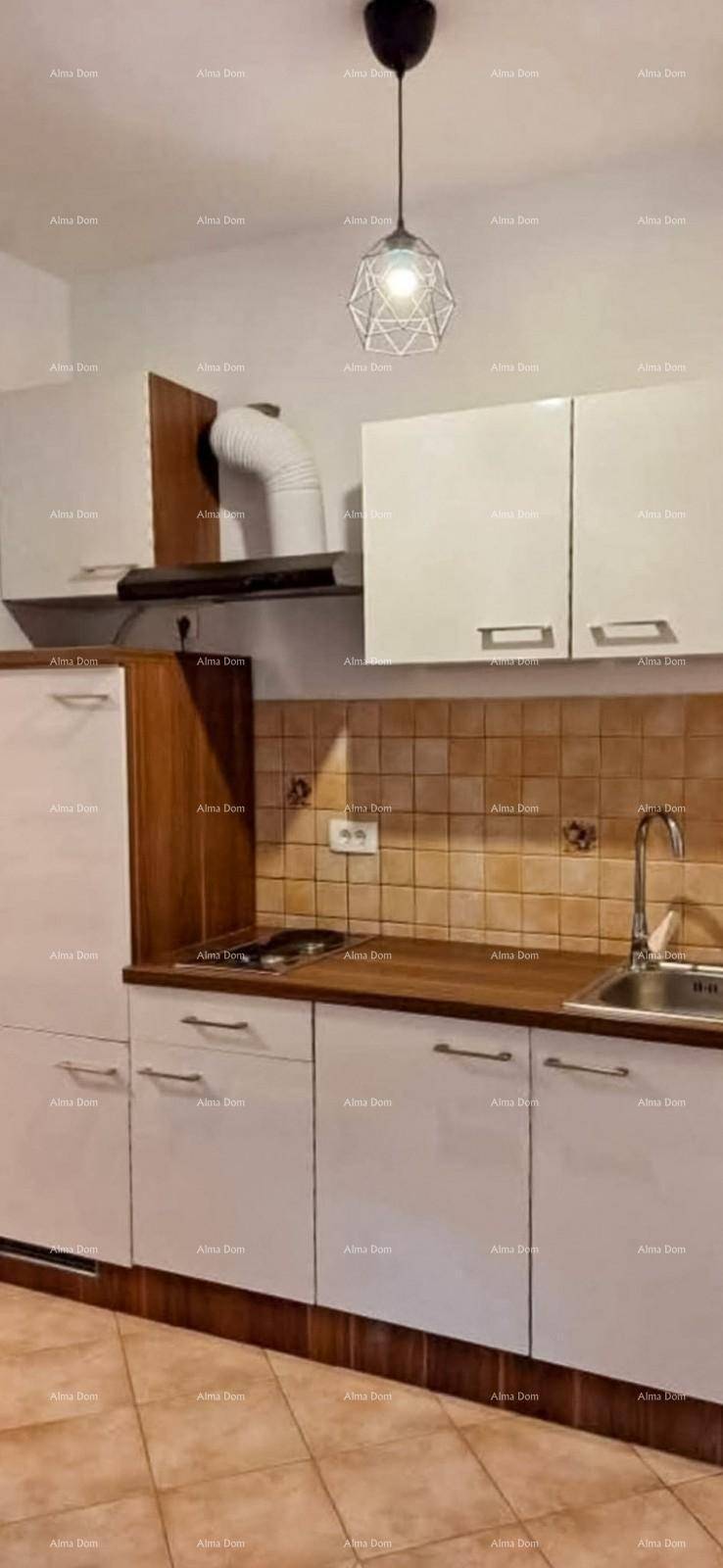 Küchenzeile mit weißen Schränken, Holz-Arbeitsplatte, Spüle und Dunstabzugshaube über dem Kochfeld.