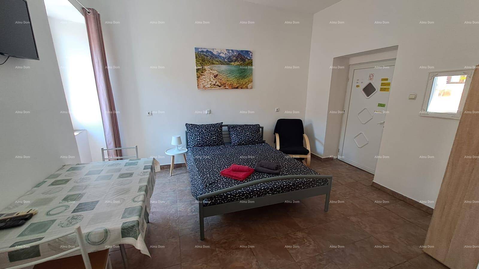 Studio-Apartment mit Schlafbereich, Esstisch und Kunst an der Wand, funktional und hell eingerichtet.