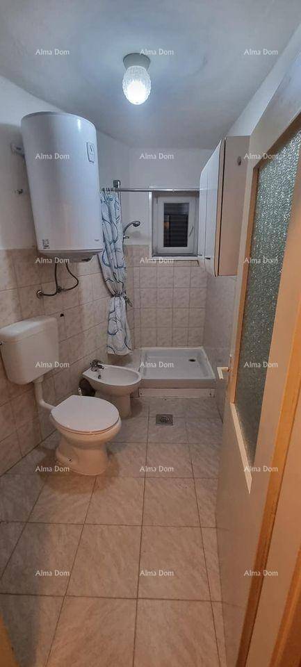 Funktionales Badezimmer mit Fliesenboden, Toilette, Bidet, Duschbereich und kleinem Fenster.
