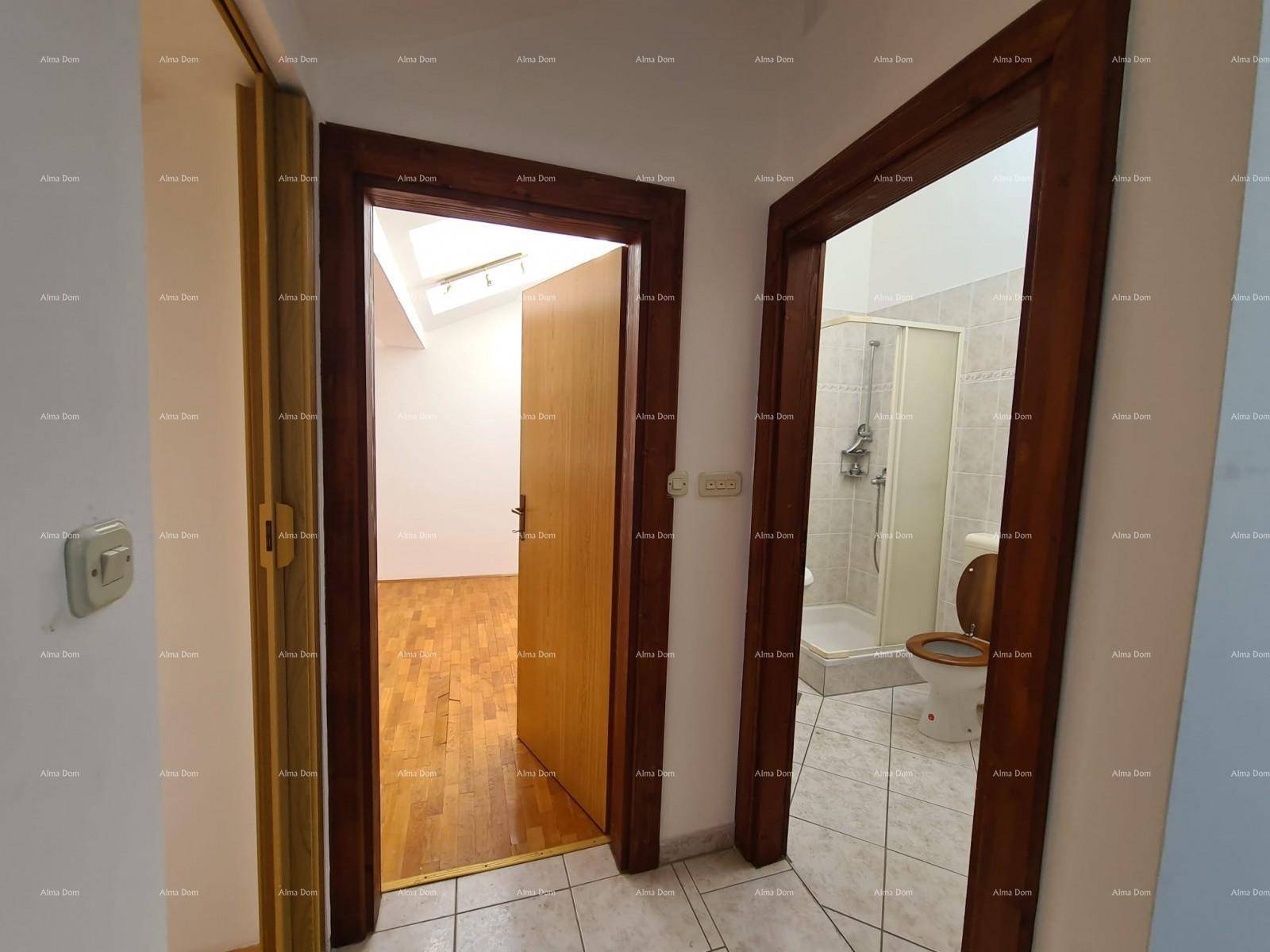 Flur mit zwei Holztüren, die zu einem Zimmer mit Parkettboden und einem Badezimmer führen.