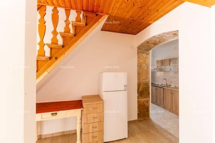 Bereich unter der Holztreppe mit Kühlschrank und Schreibtisch, angrenzend an die Küche.