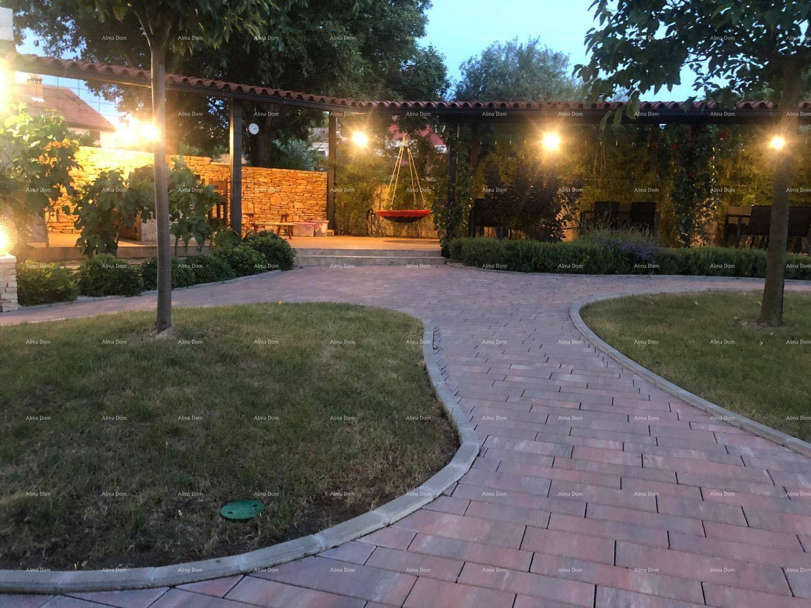 Beleuchteter Gartenbereich am Abend mit Schaukel und gepflasterten Wegen.