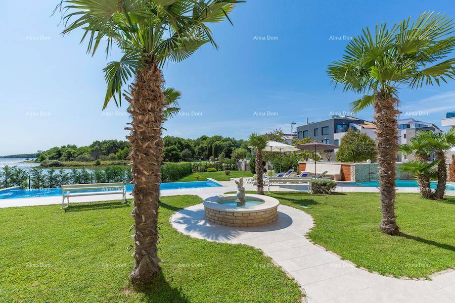 Gepflegter Garten mit Zierbrunnen, Palmen und einem Poolbereich mit Blick auf das Meer.