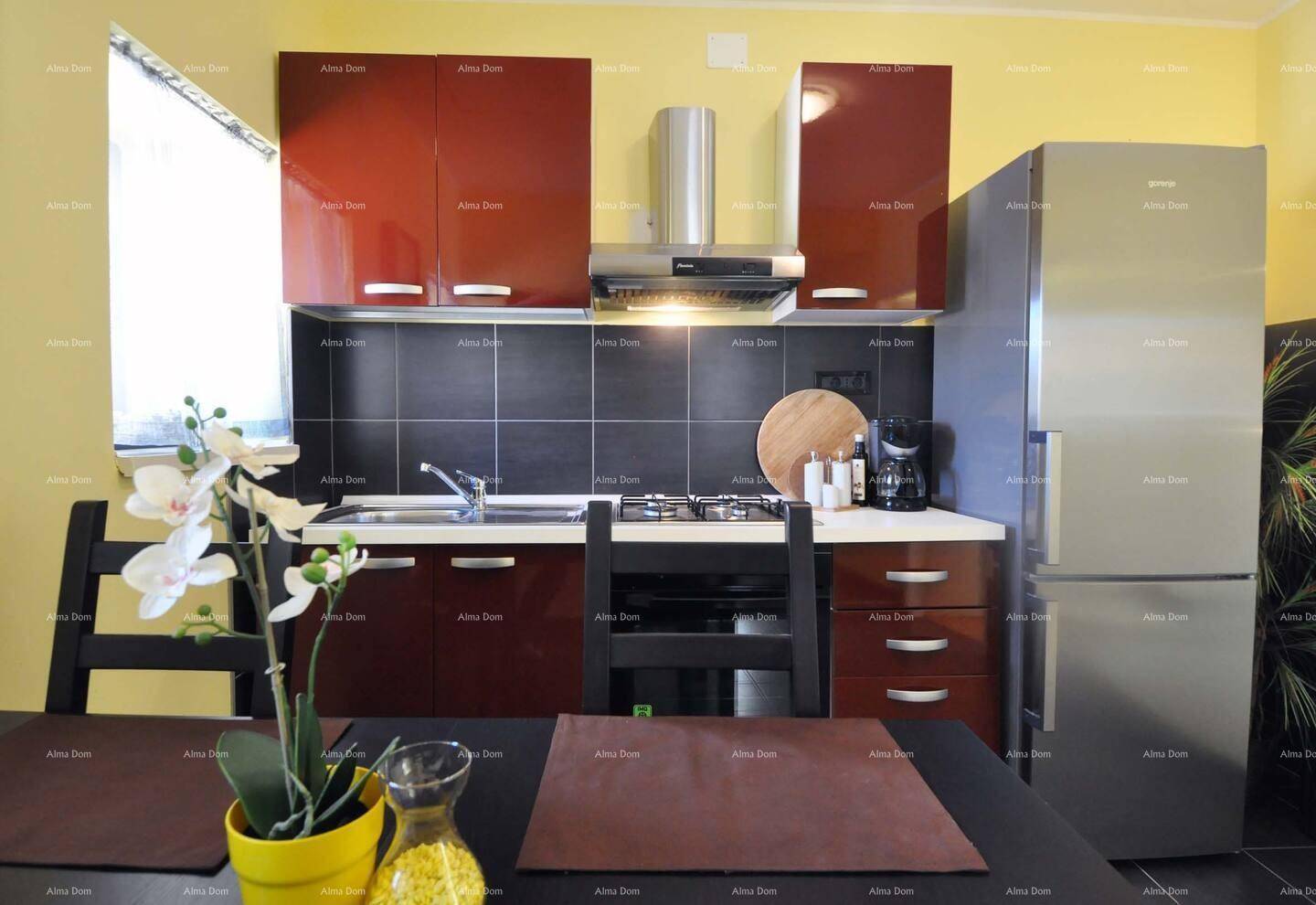 Kompakte Küche mit roten Hochglanzschränken, Edelstahlgeräten und dunklem Fliesenspiegel.