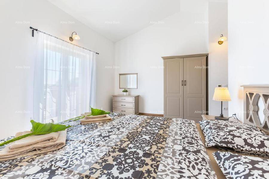 Schlafzimmer mit Kleiderschrank, Kommode und großen Fenstern für viel natürliches Licht.