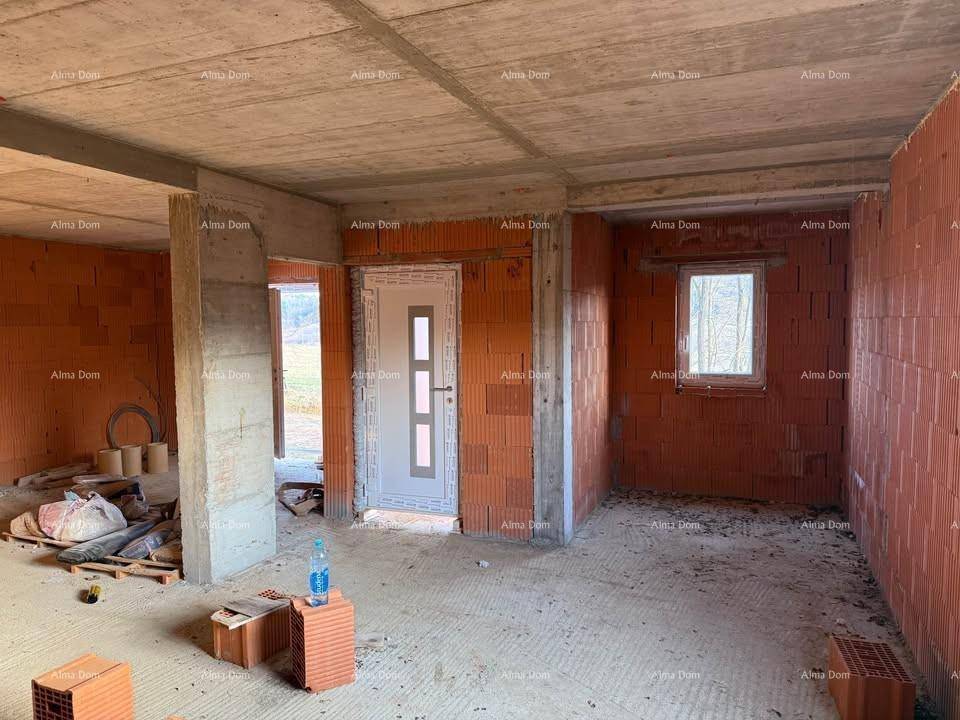 Unfertiger Innenraum eines Neubaus mit Ziegelwänden, Betonboden und sichtbaren Deckenbalken.