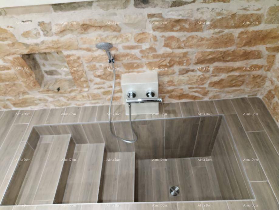 Einzigartiges Badezimmer mit begehbarer Dusche und gefliesten Stufen, umgeben von rustikalen Steinwänden.