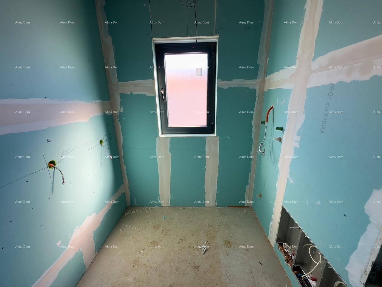 Badezimmer im Rohbau mit blauen Trockenbauplatten und einem Fenster, das natürliches Licht hereinlässt.