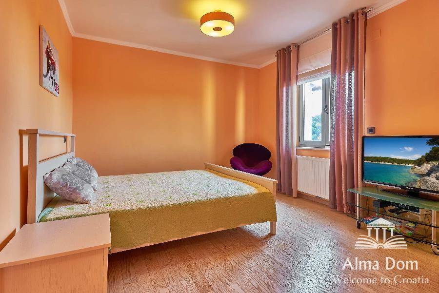 Gemütliches Schlafzimmer mit orangefarbenen Wänden, hellem Holzboden und Einzelbett.
