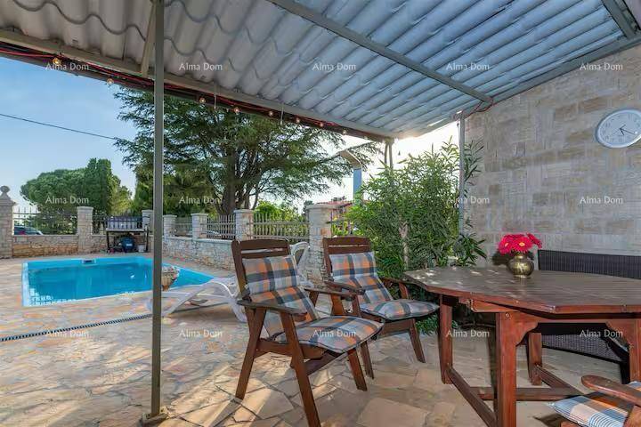 Gemütliche überdachte Terrasse mit Holztisch und Stühlen, ideal für Mahlzeiten im Freien am Pool.