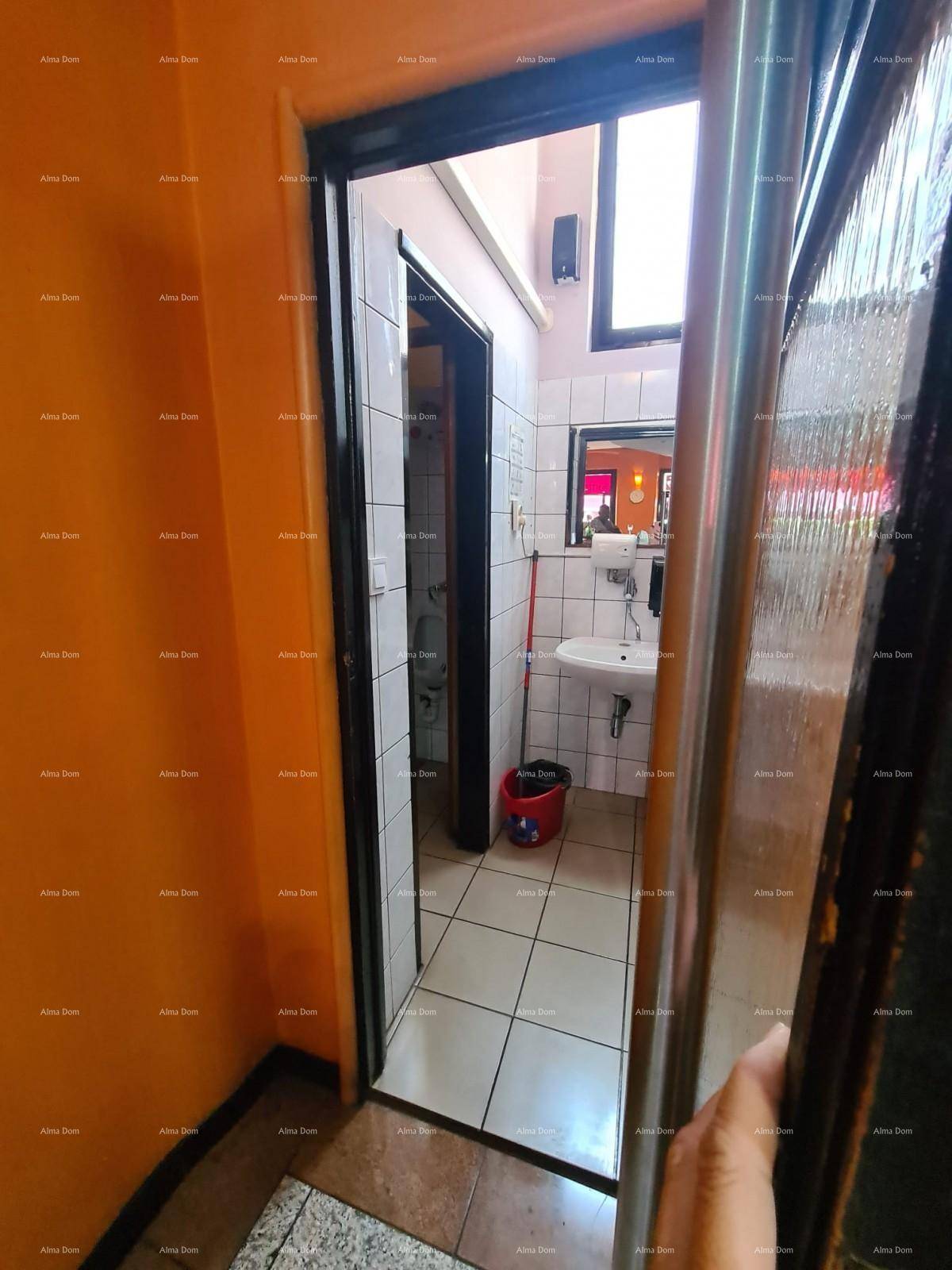 Eingangsbereich zu den Toiletten mit gefliestem Boden und einem Waschbecken im Hintergrund.