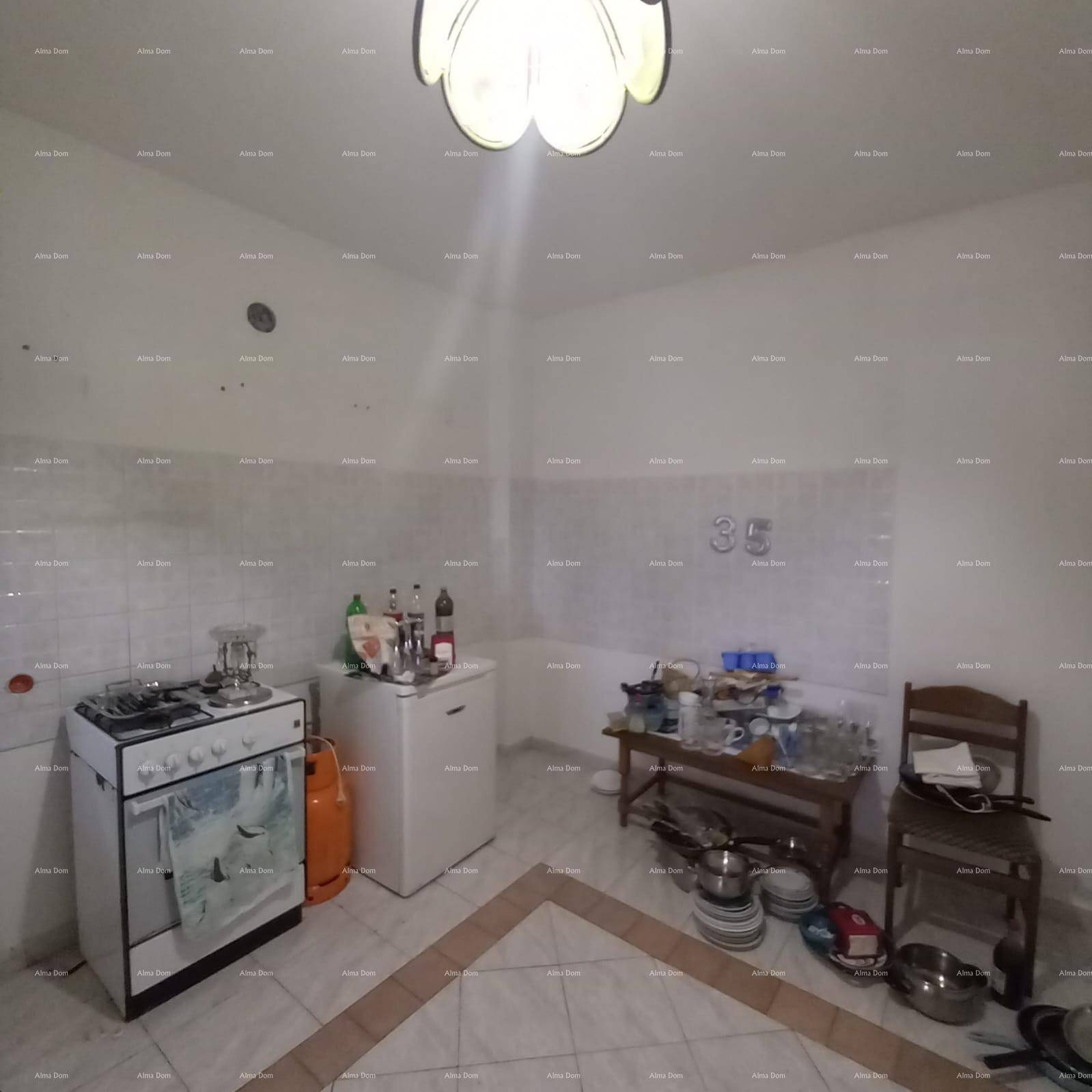Einfache Küche mit Gasherd, Kühlschrank und Fliesenboden, bereit zur Nutzung.