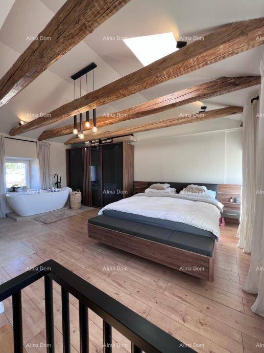 Geräumiges Schlafzimmer mit freistehender Badewanne, Holzbalken und Dachfenster für viel Tageslicht.