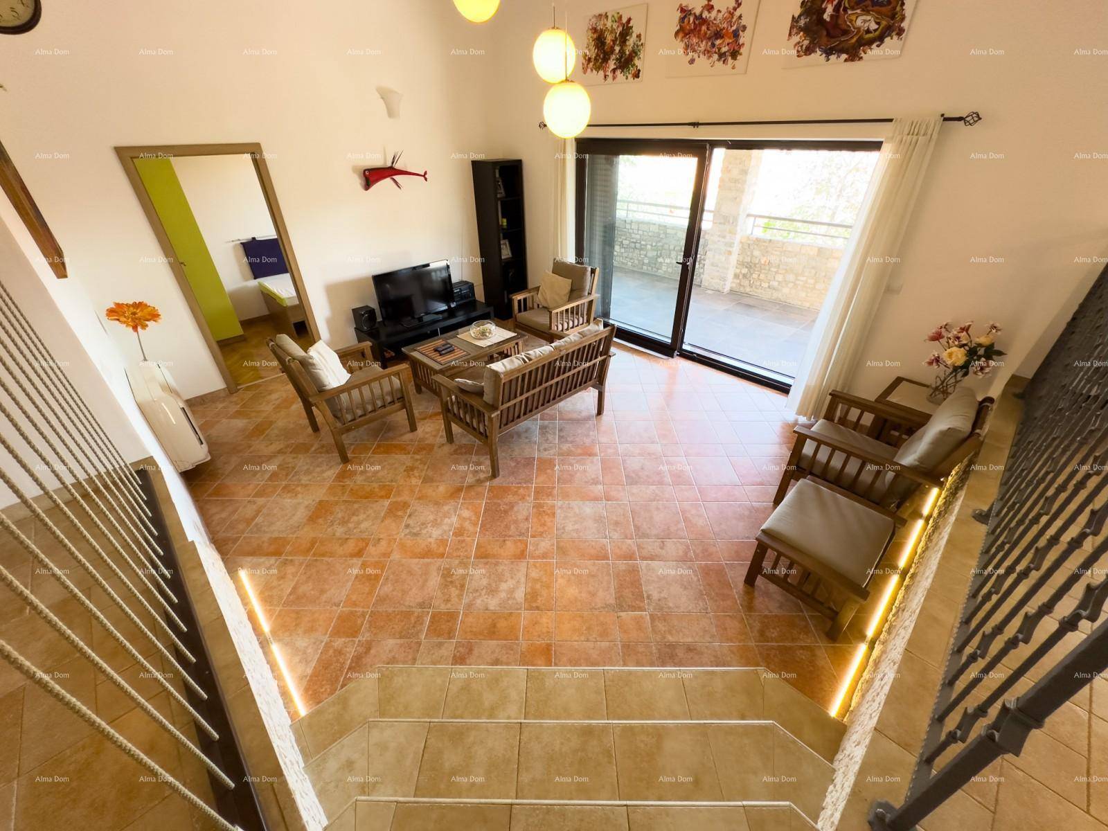 Blick von der Treppe in den Wohnbereich mit Terrakotta-Fliesenboden und großen Schiebetüren zur Terrasse.