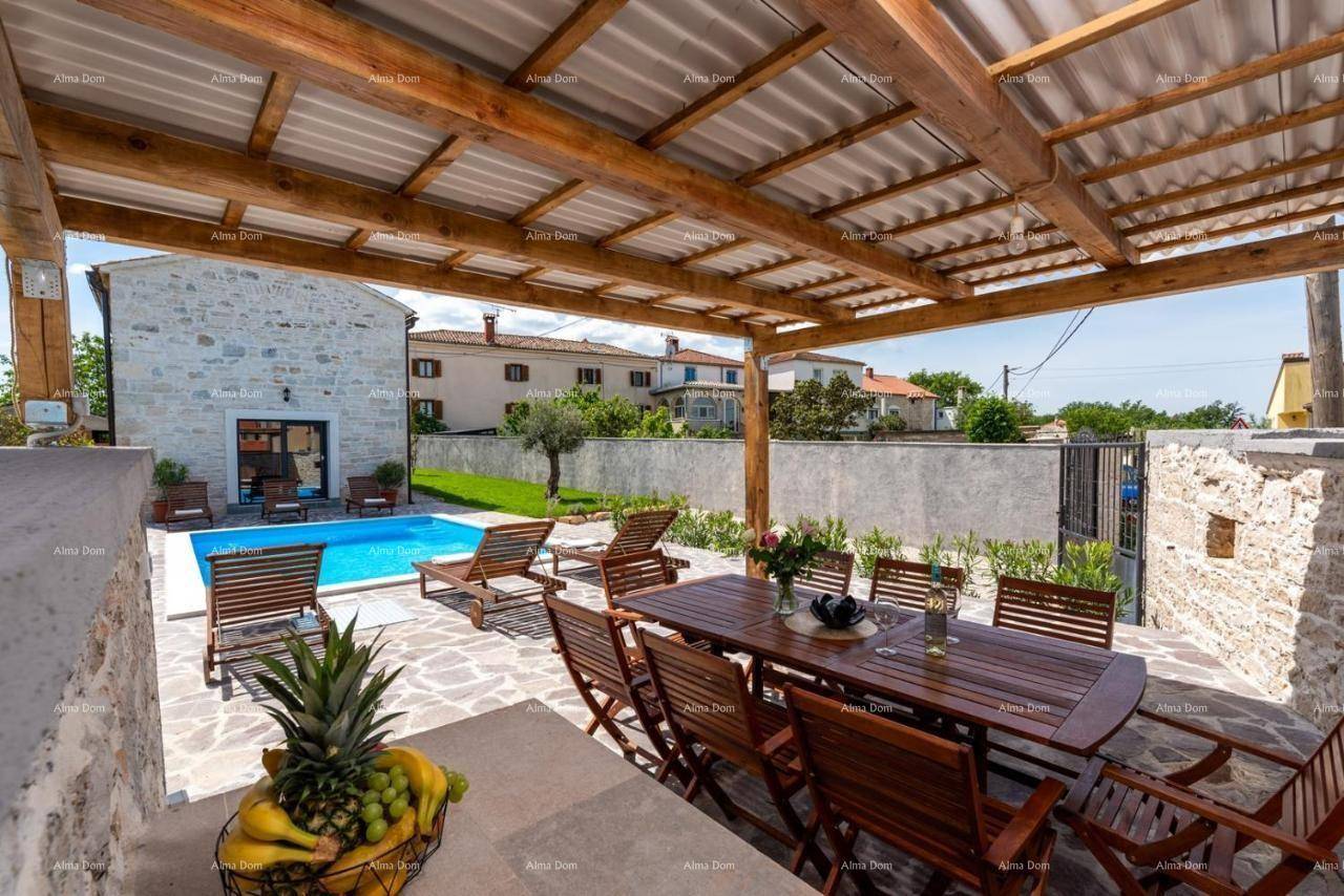 Überdachte Terrasse mit großem Holzesstisch und Stühlen, ideal für Mahlzeiten im Freien mit Poolblick.