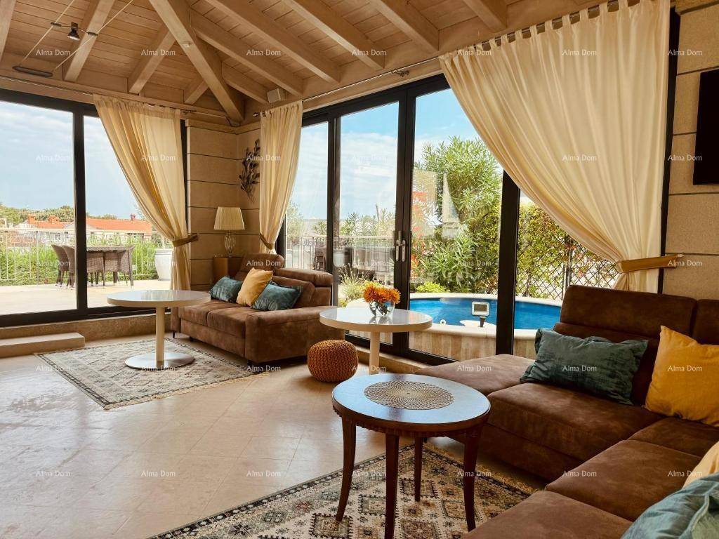 Gemütliches Wohnzimmer mit großen Glasfronten, Holzbalkendecke und direktem Zugang zum Poolbereich.